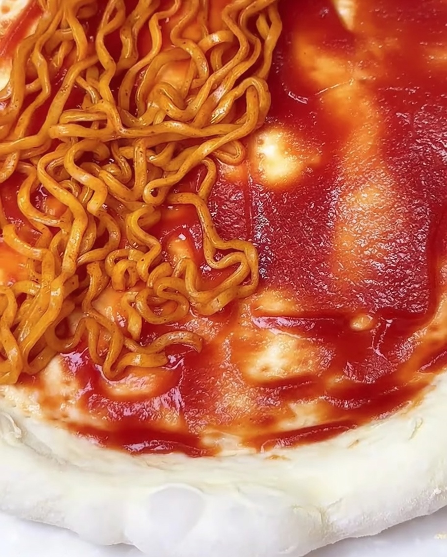 토마토 소스를 바른 도우 위에 조리된 불닭라면과 김가루가 올려진 모습.