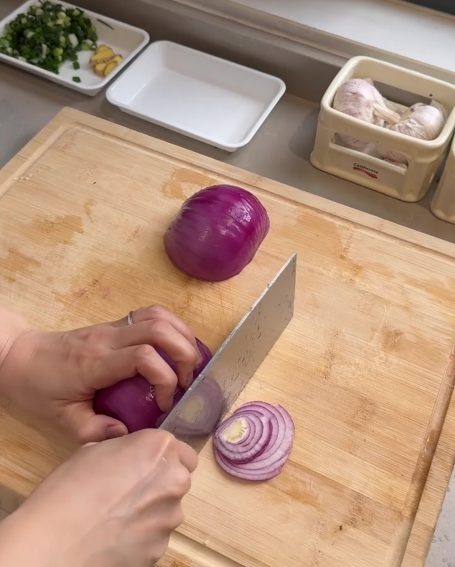도마 위에서 양파를 얇게 채 써는 모습