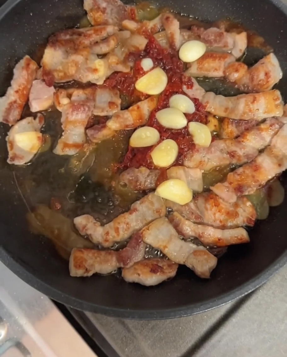 삼겹살과 마늘이 양념과 함께 어우러지게 볶아지는 모습.