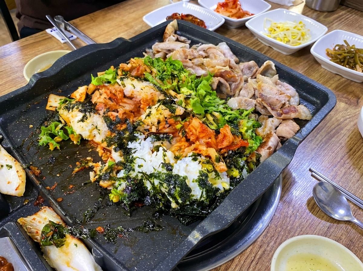 나무 주걱 두 개로 밥, 고기, 채소, 김치, 달걀을 섞으며 볶는 모습.