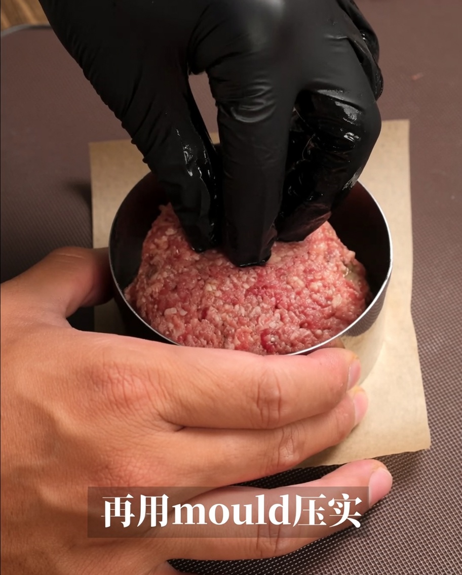 생고기 반죽을 금속 링 틀에 눌러 담아 완벽한 햄버거 패티 모양을 만드는 모습.