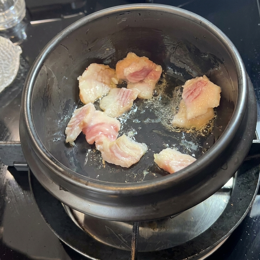 뚝배기에서 돼지고기가 익으며 기름이 나오는 모습.