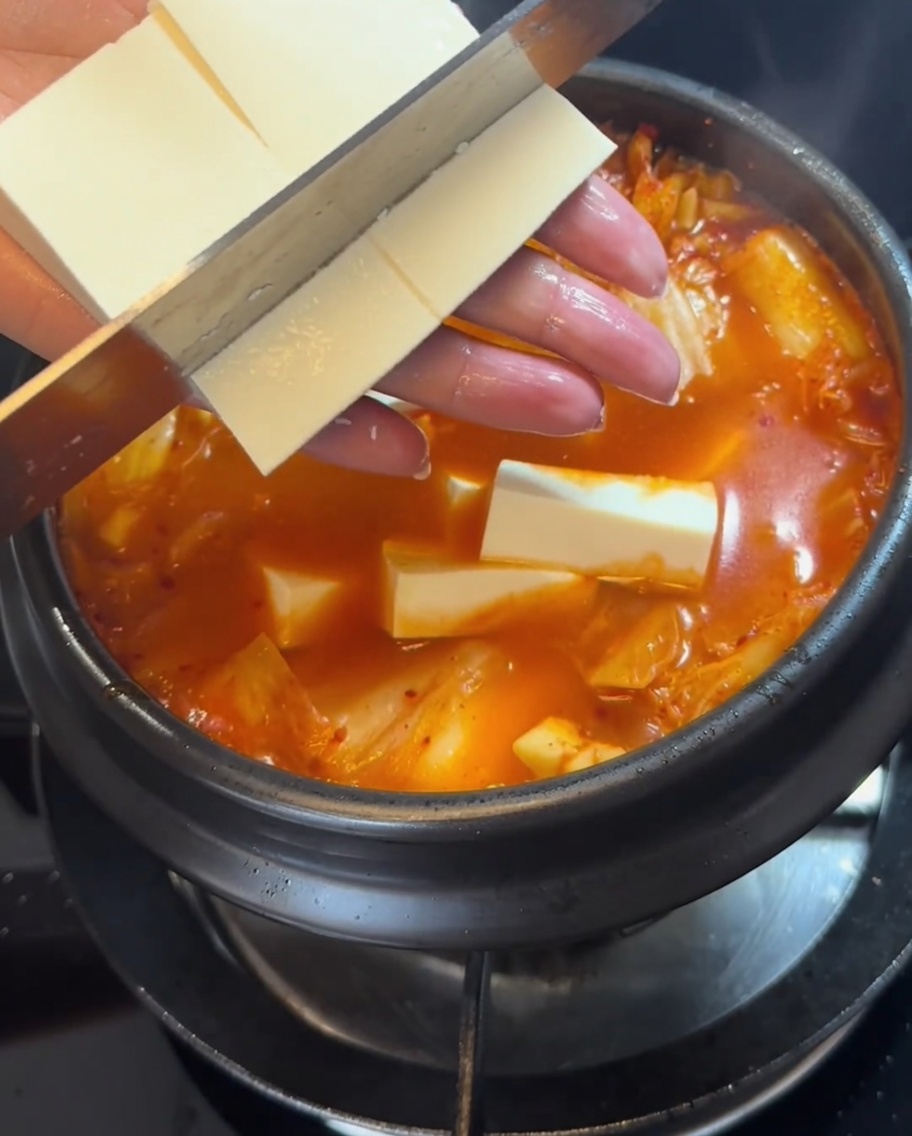 찌개에 두부를 조심스럽게 넣는 모습.