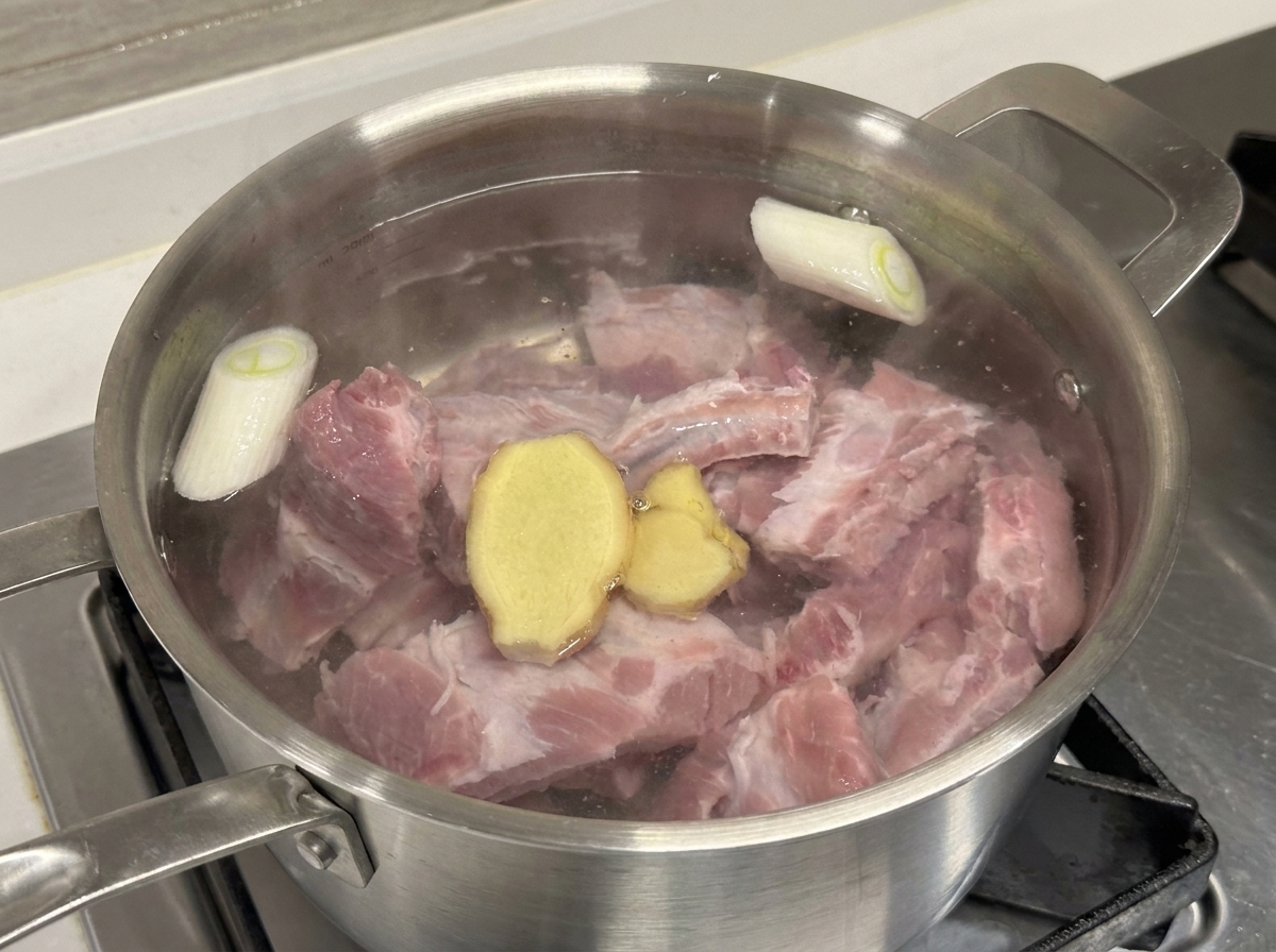 생돼지갈비, 대파, 생강 편이 든 냄비에 맛술을 붓는 모습.