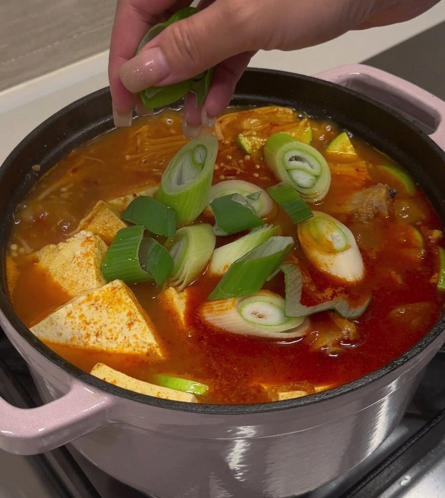 완성된 돼지갈비 김치찌개 위로 송송 썬 대파와 청홍고추를 흩뿌리는 모습.