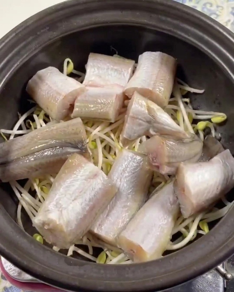 검은 뚝배기 바닥에 깔린 콩나물 위로 생명태 토막들이 가지런히 놓여 있는 모습.