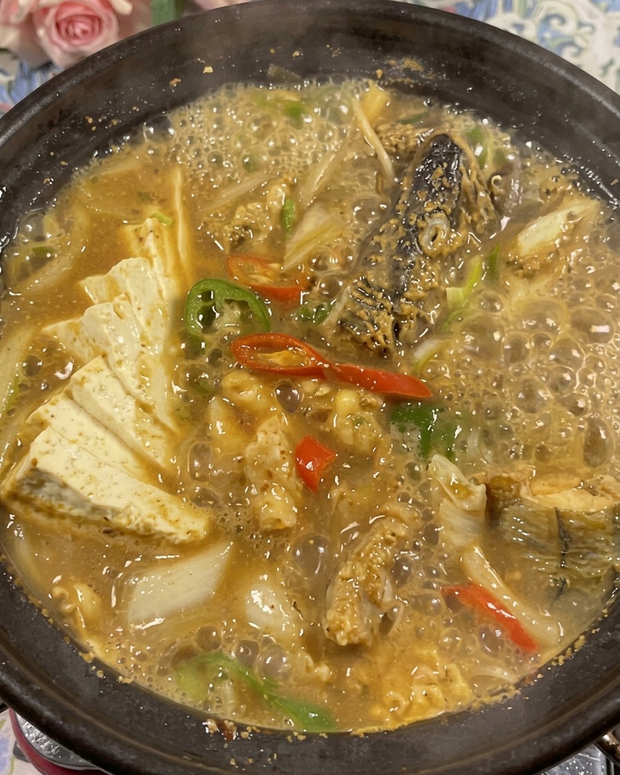 진하게 끓여진 명태 된장찌개 위에 신선한 고수를 듬뿍 올려 장식한 뚝배기.