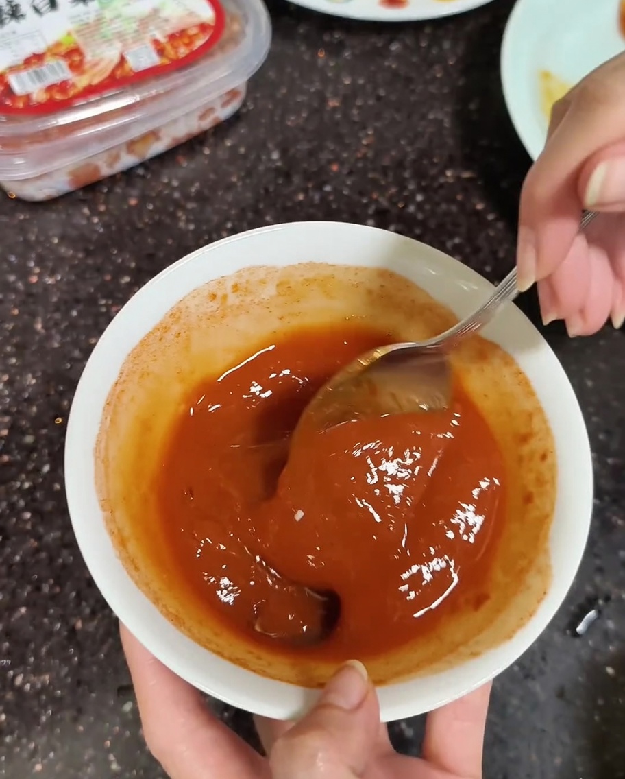 된장과 고추장을 소량의 물과 함께 숟가락으로 매끄럽게 섞는 클로즈업.