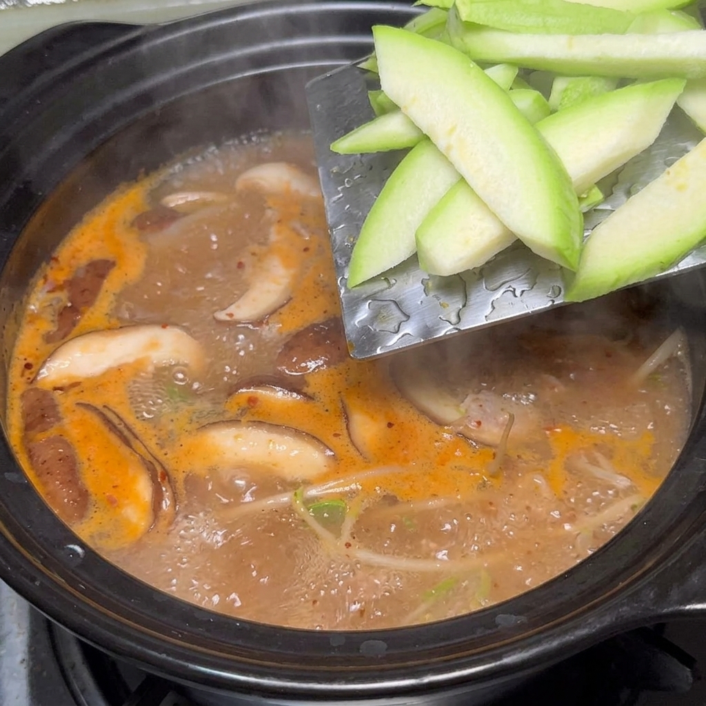 끓는 찌개에 애호박을 넣는 모습.