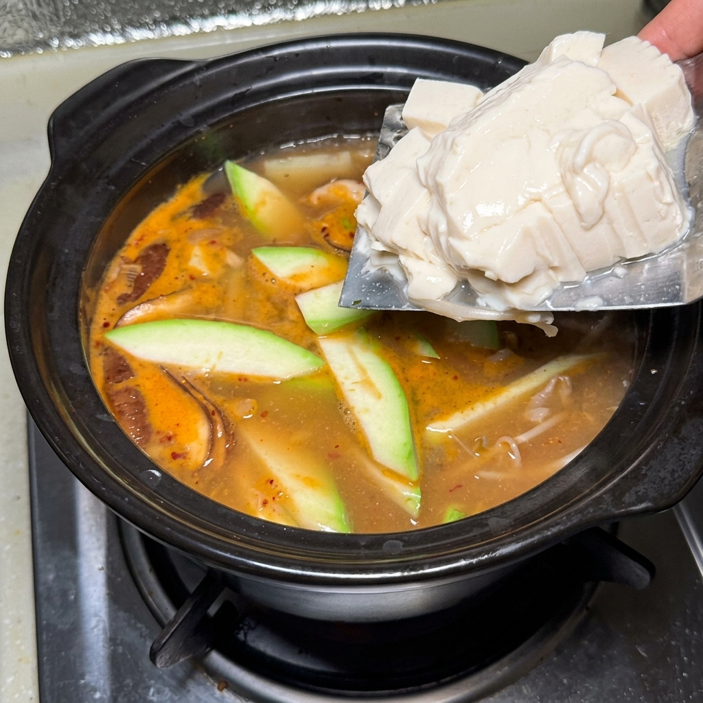 끓는 찌개에 연두부를 조심스럽게 넣는 모습.