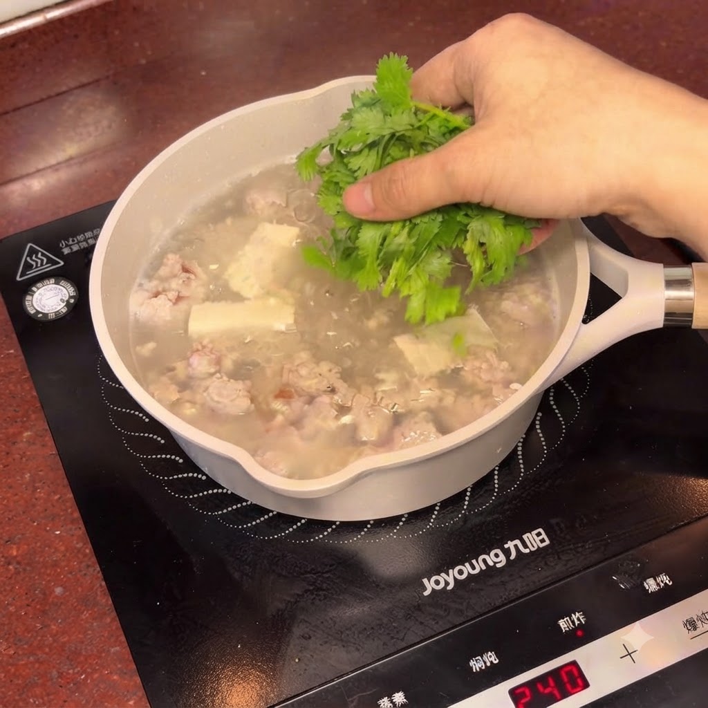 김이 모락모락 나는 매실 두부 완자탕에 잘게 썬 신선한 고수를 뿌리는 모습.