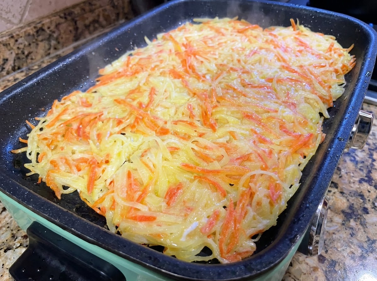 팬 안에서 요리용 뒤집개를 이용해 커다란 감자 팬케이크를 더 작은 조각으로 나누어 자르는 모습.
