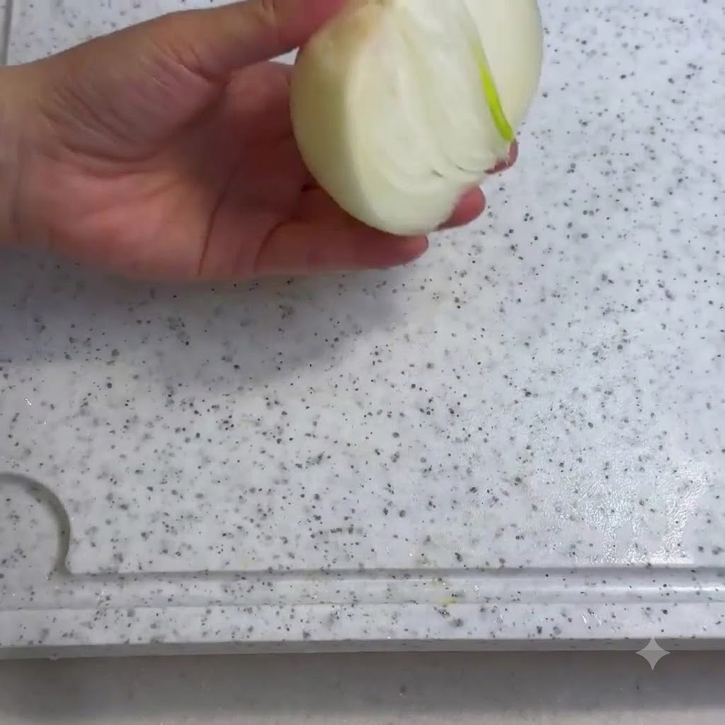 하얀 도마 위에서 칼로 양파를 썰고 있는 모습.
