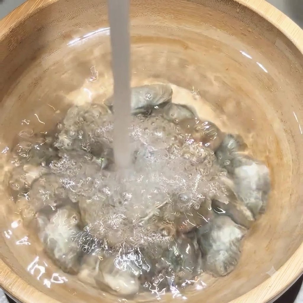 나무 볼 안의 조개 위에 흐르는 수돗물이 직접 붓는 모습.