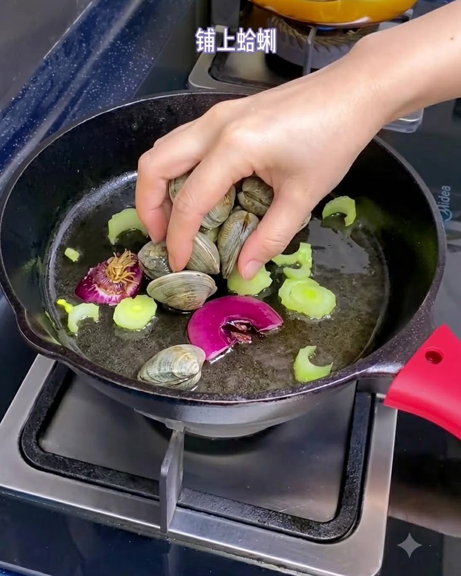 올리브 오일, 샬롯 조각, 썰어둔 셀러리가 채워진 팬에 손으로 신선한 조개를 넣는 모습.
