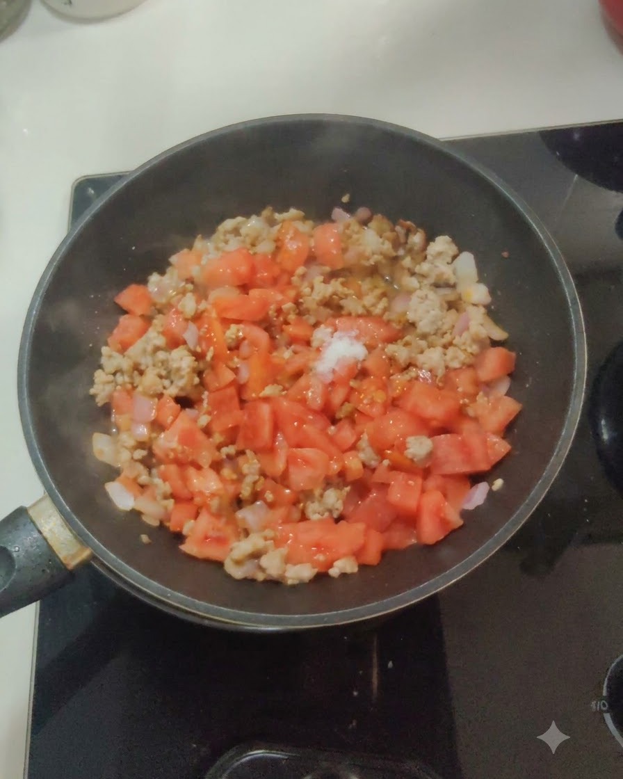 팬 안의 토마토, 양파, 고기 혼합물 위에 소금과 설탕을 뿌리는 모습.
