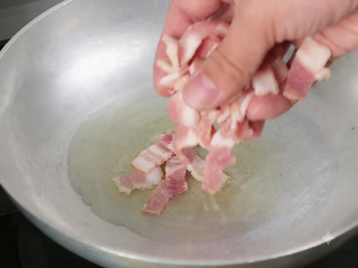 뜨거운 올리브 오일이 둘러진 팬에 베이컨 조각을 넣는 모습.