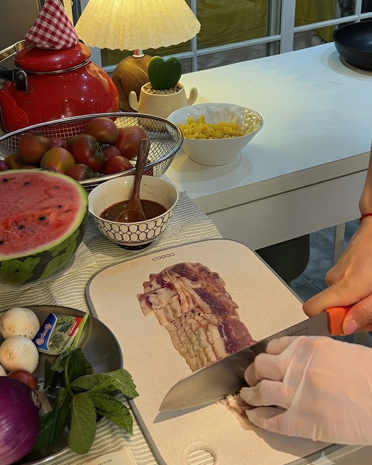 버섯과 신선한 민트 접시 옆 도마 위에서 적양파를 반으로 썰고 있는 모습.