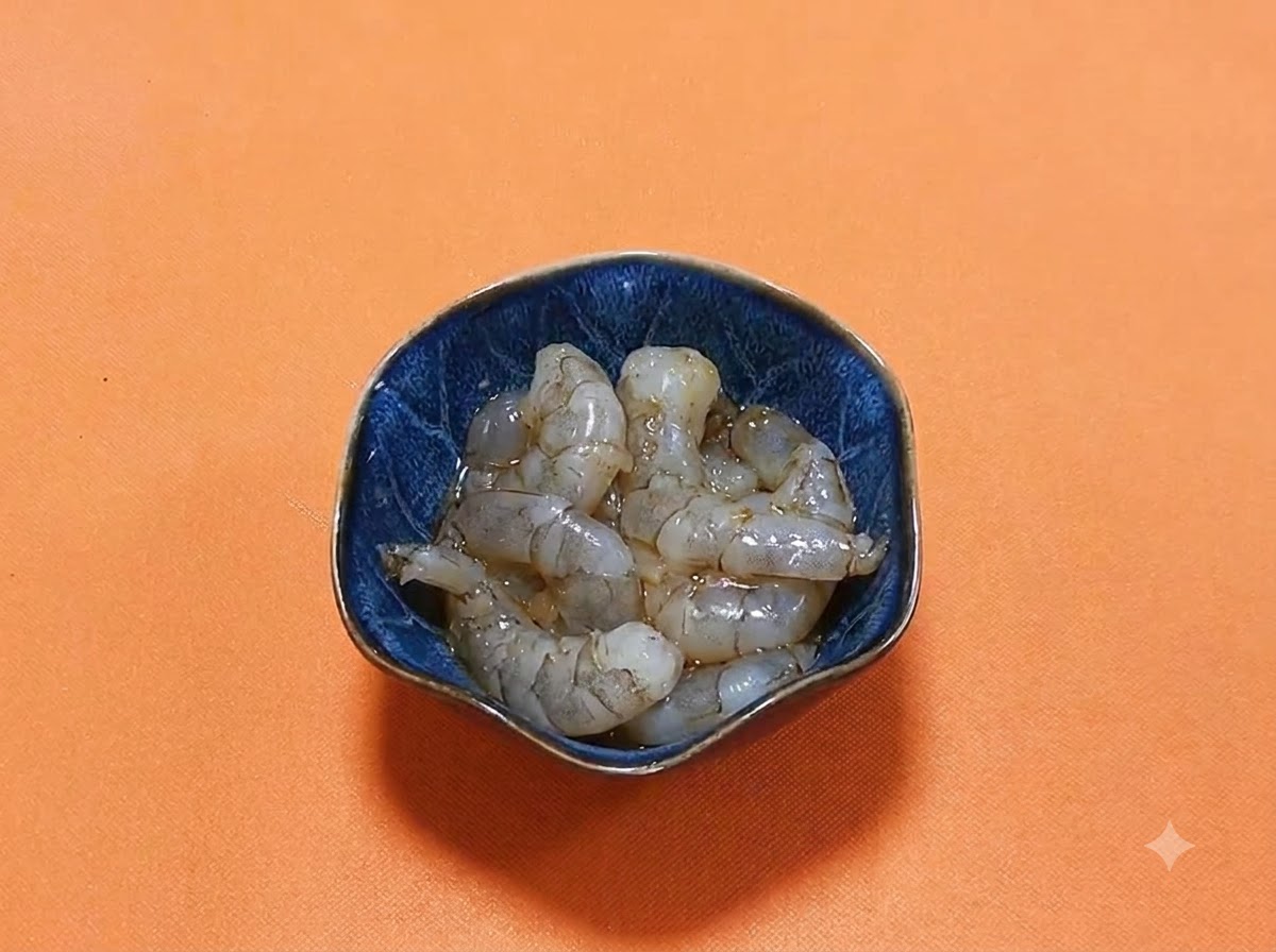 진간장과 향신료 양념이 광택을 내며 담겨 있는 진청색 볼 안의 껍질 벗긴 생새우.