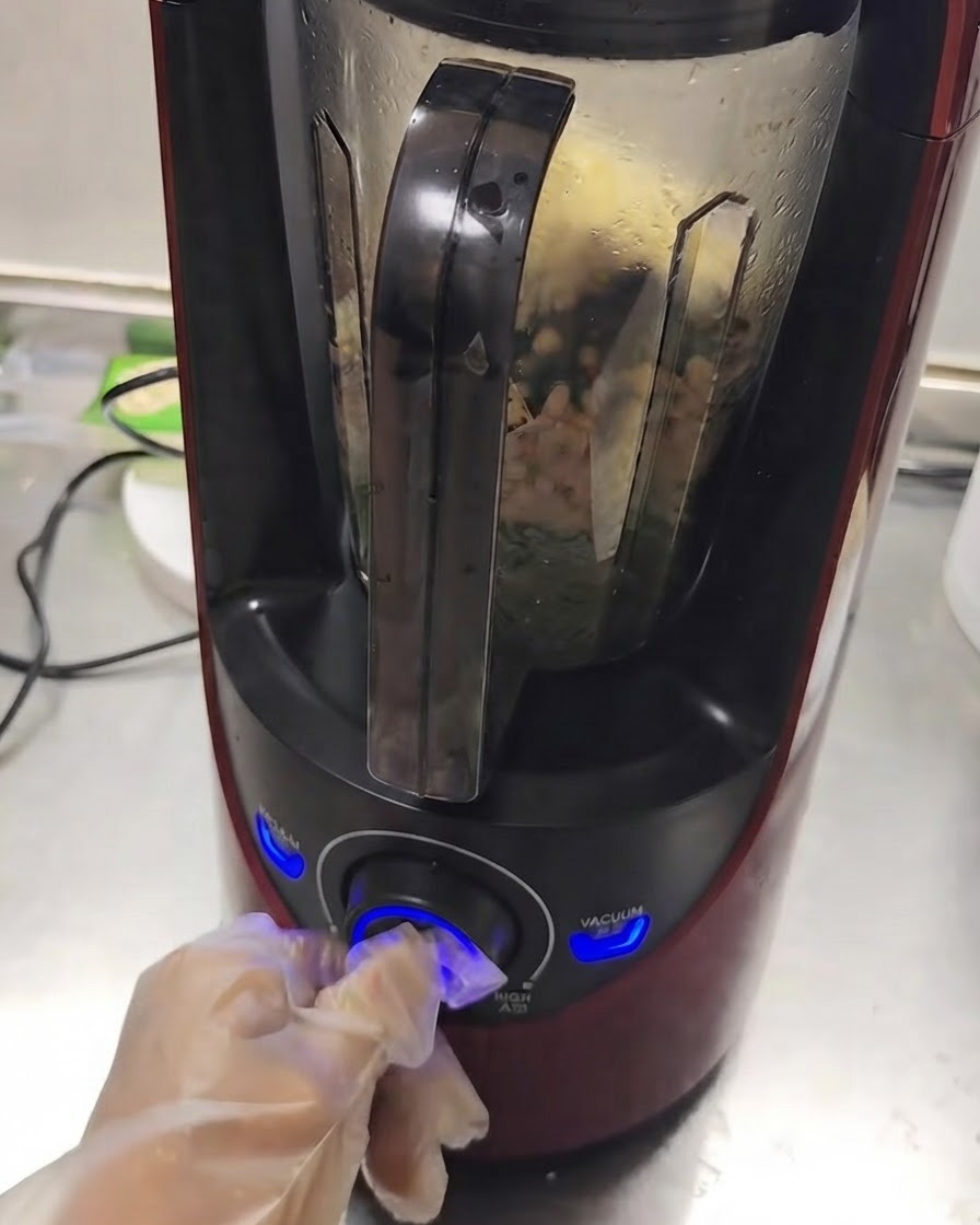 한 손으로 다이얼을 돌리는 동안 내부에서 재료가 섞이고 있는 작동 중인 블렌더.