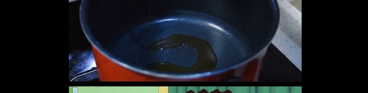 어두운 색 조리 냄비 바닥에 얇게 두른 참기름이 데워지는 모습.