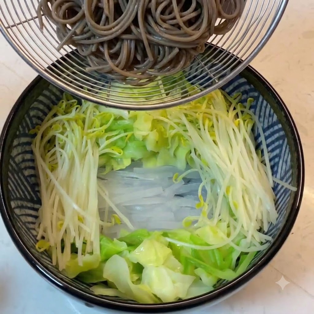 채소가 담긴 그릇 위 철망 거름망에 담겨 있는 삶은 메밀면.