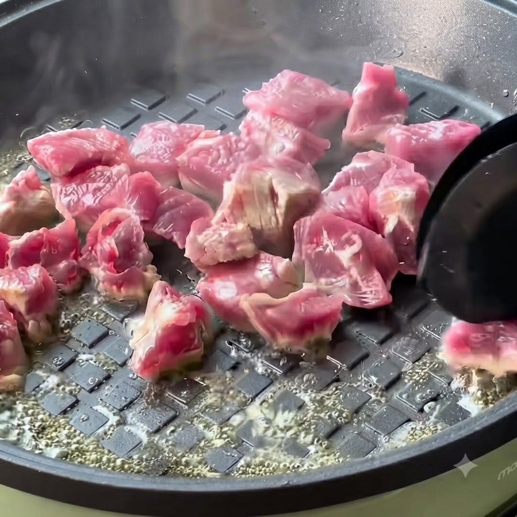 달궈진 팬에서 소고기 큐브가 익어가며 노릇하게 구워지는 모습.