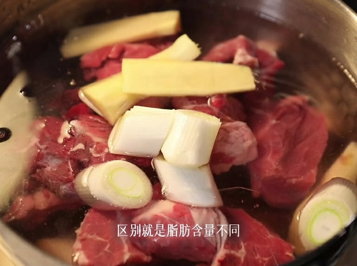 생강과 대파 조각을 넣은 찬물이 담긴 냄비에 생고기 양지 조각이 잠겨 있는 모습.