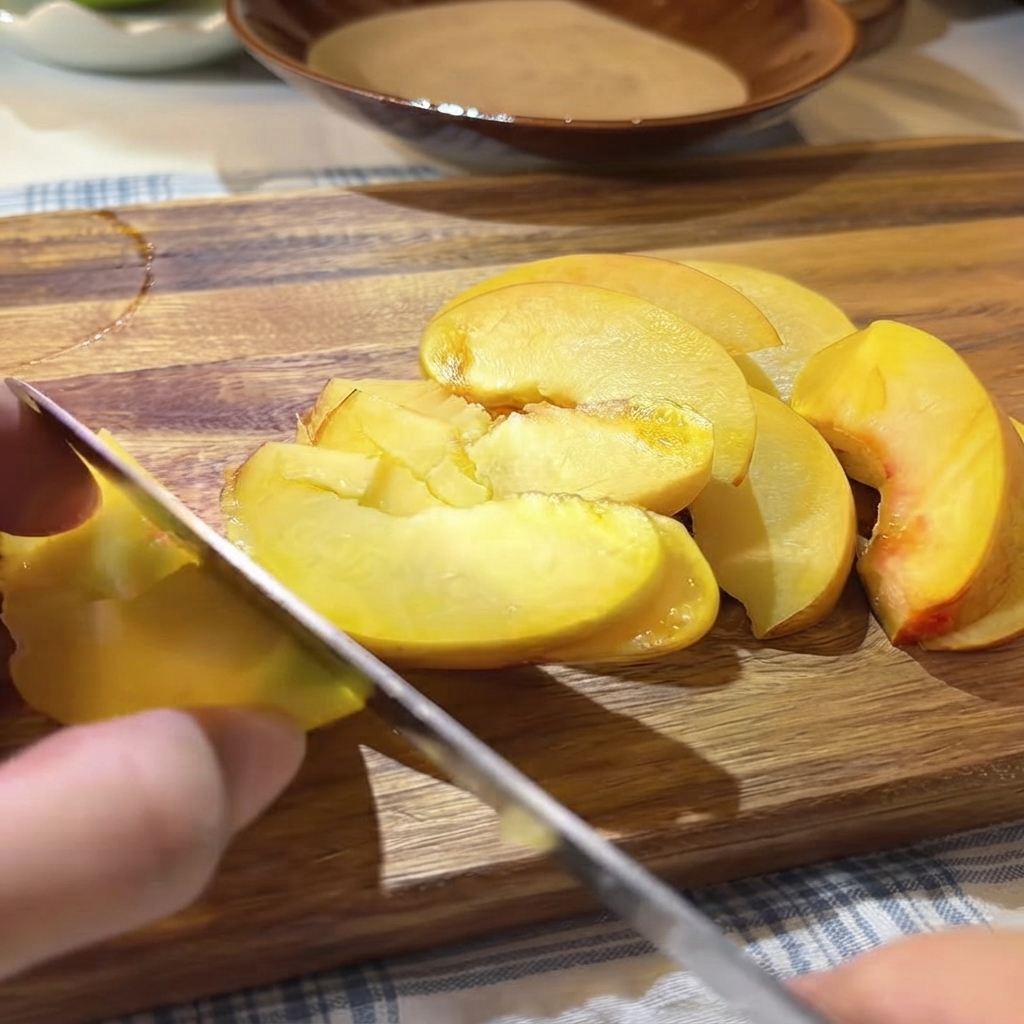 도마 위의 썰어둔 노란 붉은 복숭아 위에 신선한 패션후르츠 씨와 과육을 숟가락으로 얹는 모습.