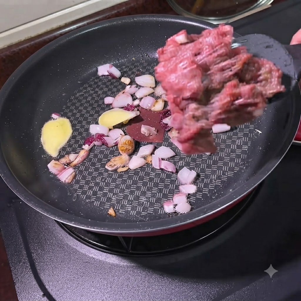 양파와 생강 조각이 볶아지고 있는 팬에 주걱으로 다진 소고기를 넣는 모습.