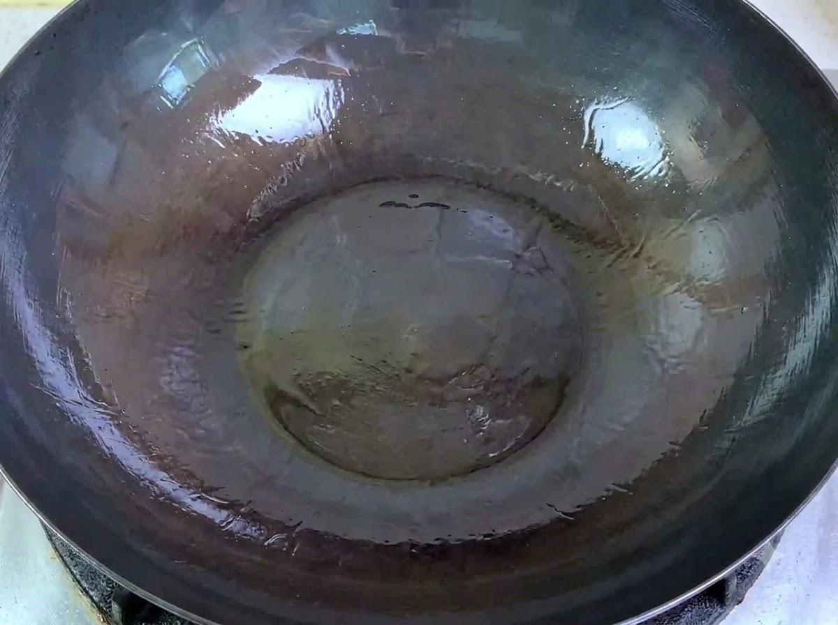 뜨거운 기름이 담긴 커다란 웍에 생 다진 돼지고기를 붓는 모습.
