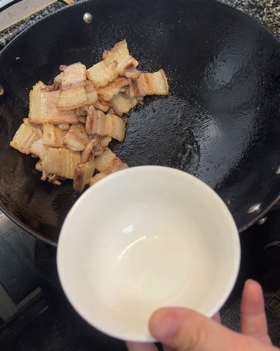 뒤집개를 이용해 웍에 고인 여분의 기름을 하얀 작은 볼에 덜어내는 모습.