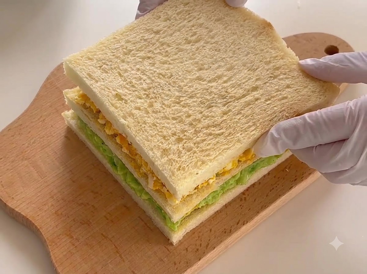 도마 위에 놓여 단면을 보여줄 준비가 된 조립된 3층 샌드위치.
