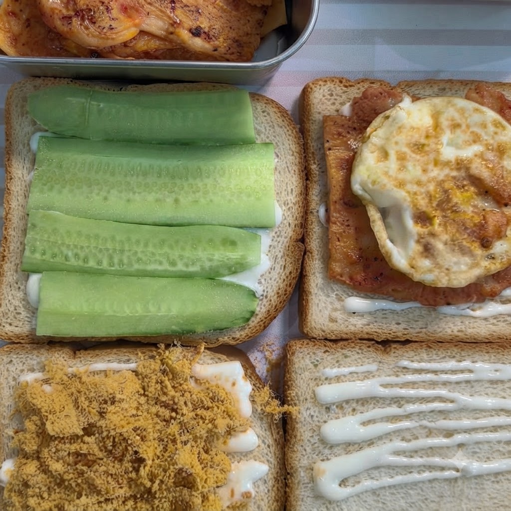 하얀 스프레드가 발린 식빵 위에 조리된 양념 치킨과 계란후라이가 얹어져 있는 모습.