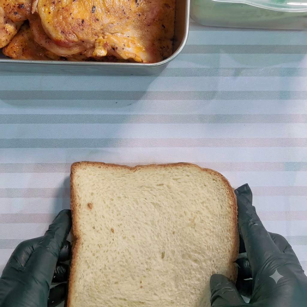 줄무늬 표면 위에서 포장된 샌드위치를 톱니 모양 칼로 대각선으로 썰고 있는 모습.