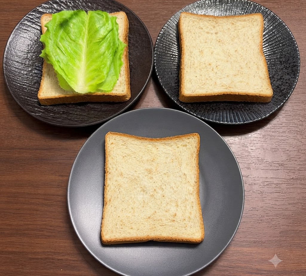 검은색 접시 위에 놓인 통밀빵 조각 위에 신선한 녹색 양상추 잎이 깔끔하게 정돈된 모습.