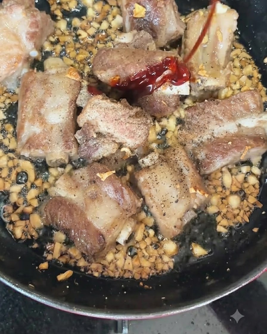 노릇하게 구워지는 돼지갈비와 다진 마늘이 담긴 뜨거운 팬에 홍고추와 청고추를 넣는 모습