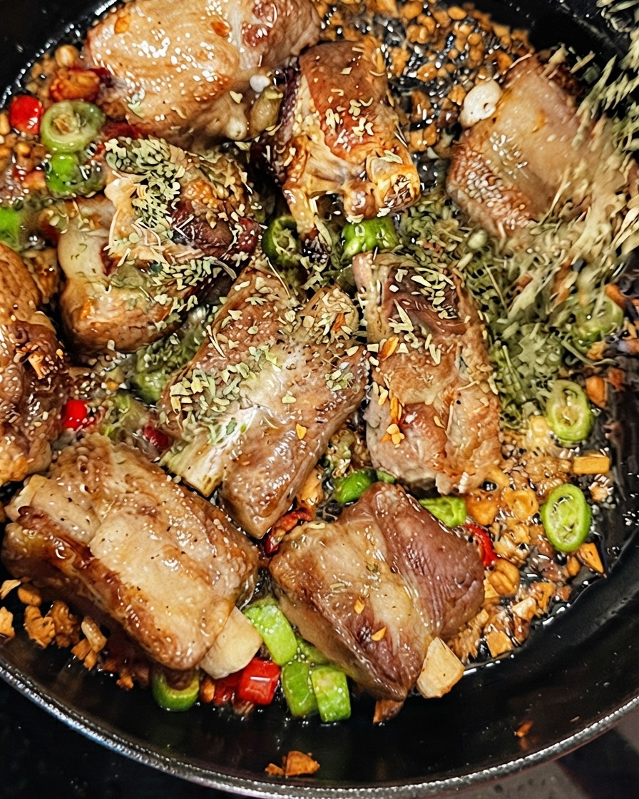 지글거리는 팬에 드라이 화이트 와인을 붓는 동안 돼지갈비 위에 건조 파슬리를 뿌리는 모습