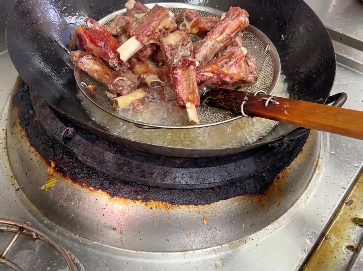 철망 바구니를 이용해 뜨거운 기름에서 건져지고 있는 튀긴 돼지갈비.