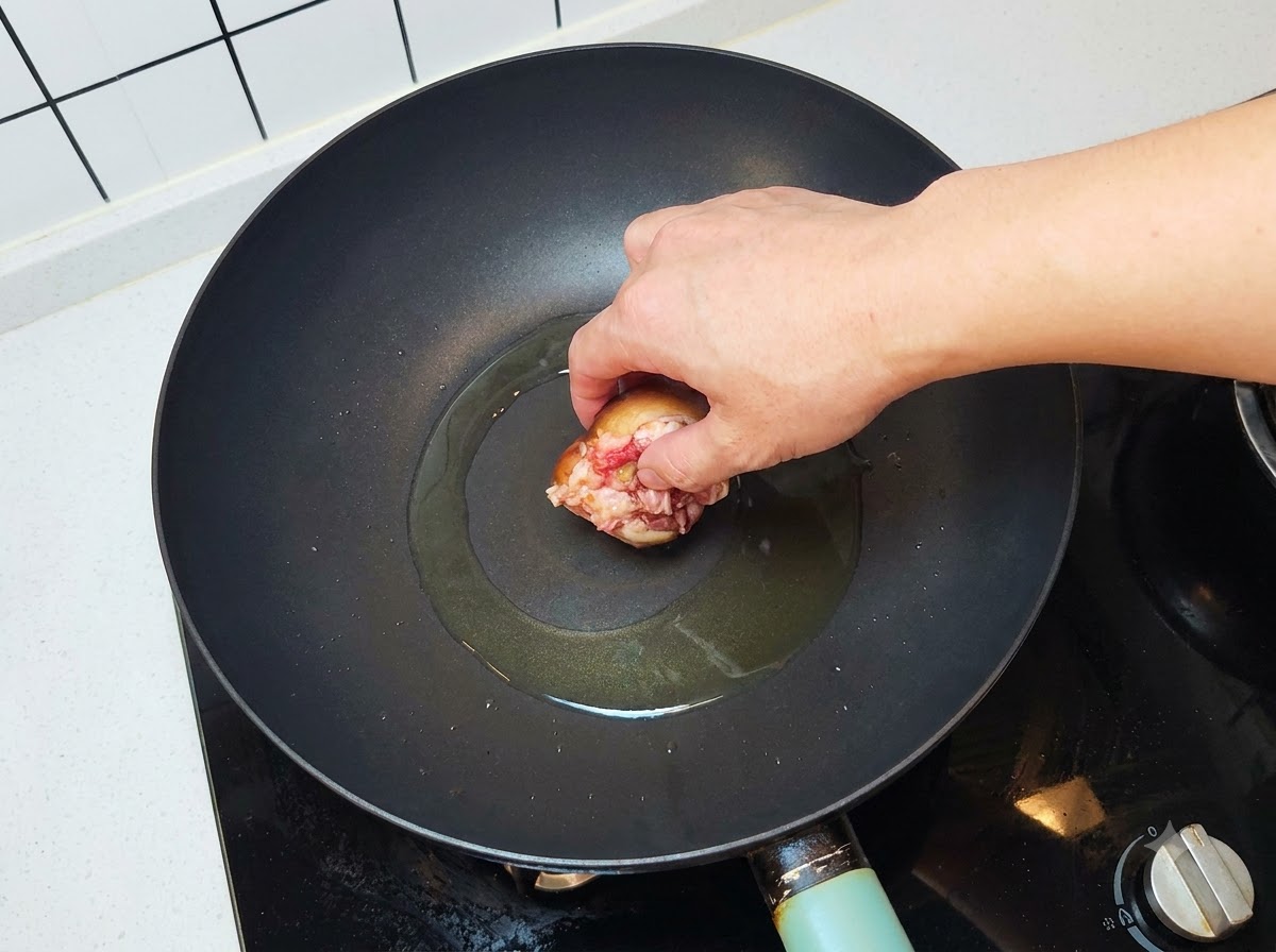 기름이 달궈진 웍에 고기 면이 아래로 향하도록 버섯을 올리는 모습