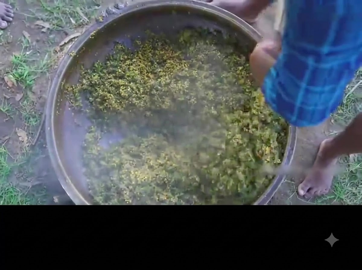 큰 철 냄비 안에서 완성된 초록색 오크라와 계란 커리를 젓고 있는 사람.