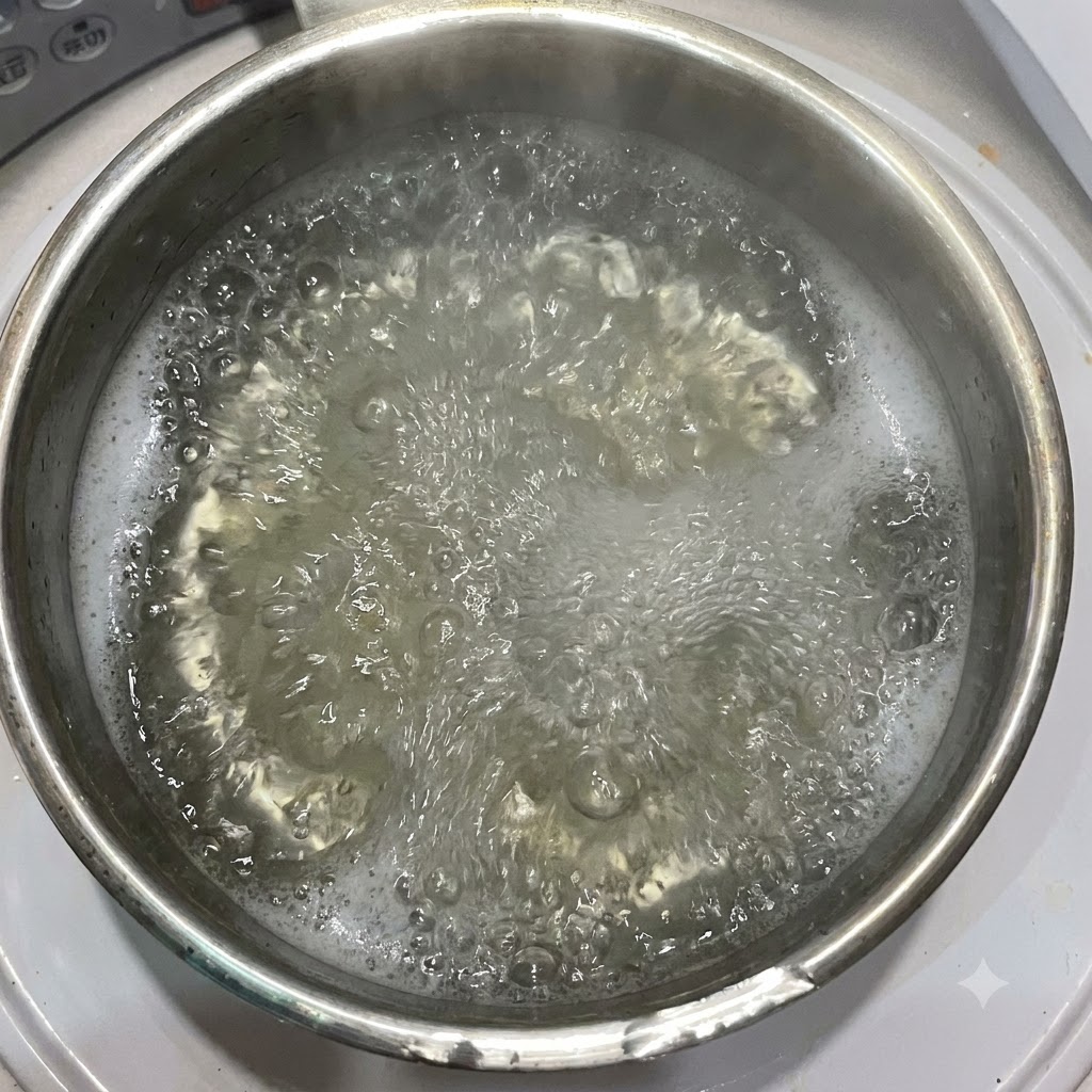 펜네 파스타가 담긴 끓는 물 냄비에 올리브 오일이 부어지고 있는 모습.