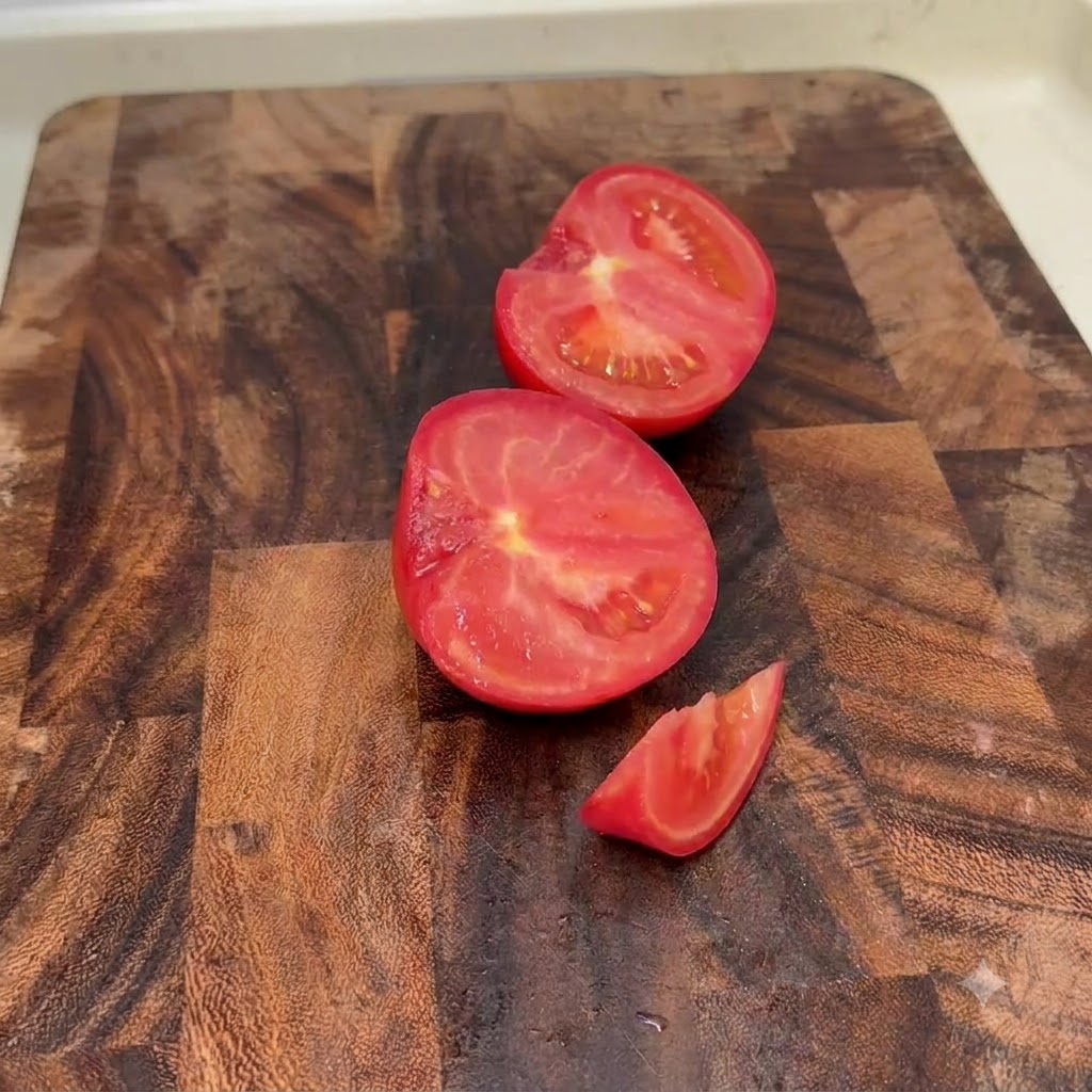 나무 도마 위에 반으로 잘리거나 작은 조각으로 썰린 신선한 토마토.