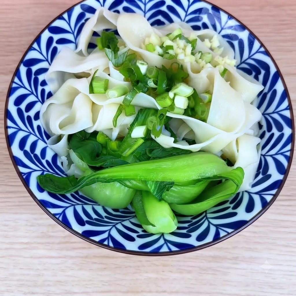 조리된 국수와 청경채를 담은 그릇 위에 다진 파와 마늘을 올린 모습.