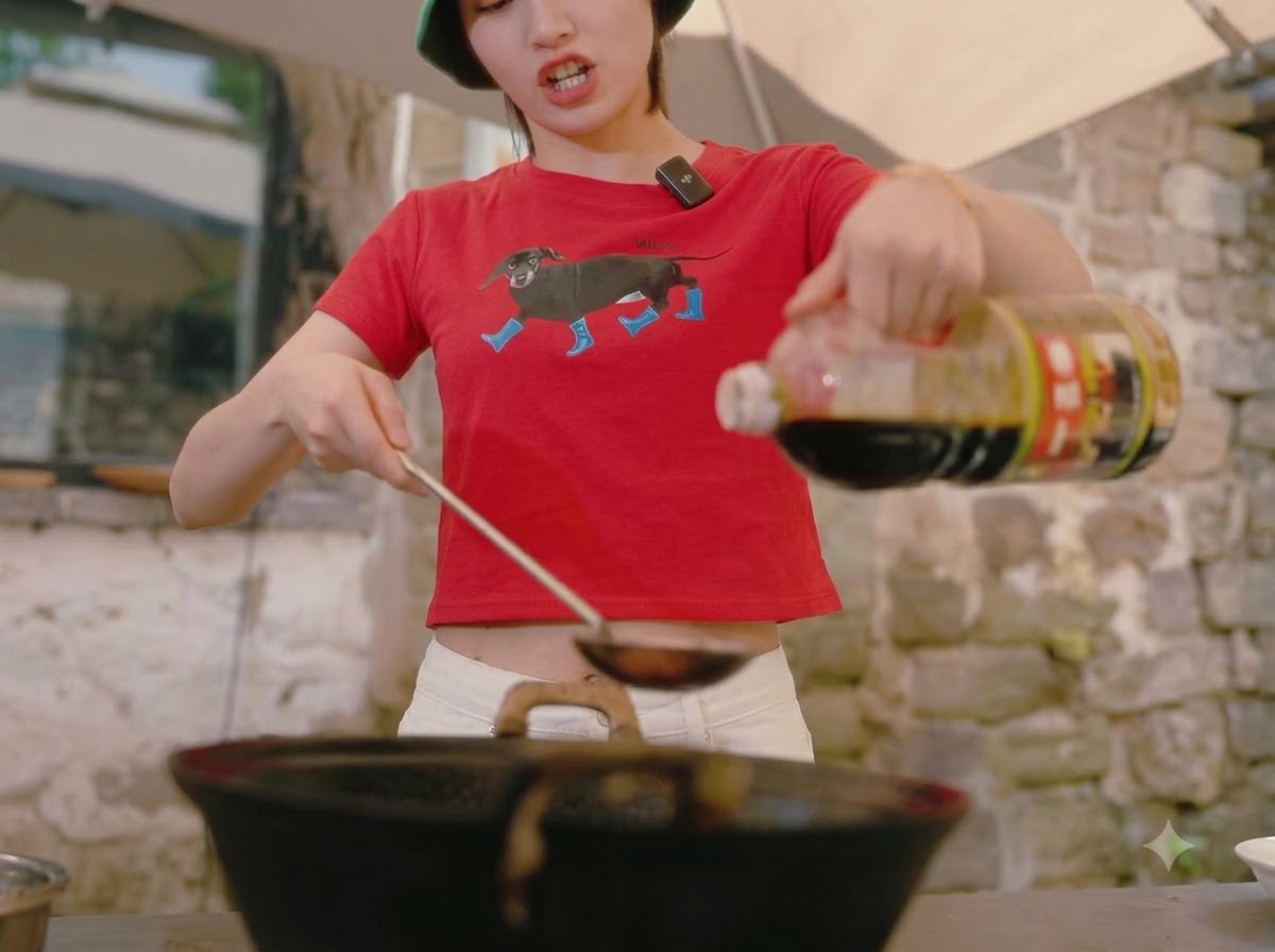 토마토 소스가 끓고 있는 웍에 병에서 진간장을 따르는 모습