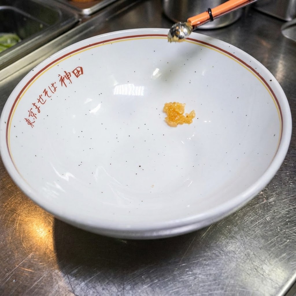 일본어가 적힌 하얀 빈 그릇 바닥에 약간의 양념장이 담겨 있는 모습.