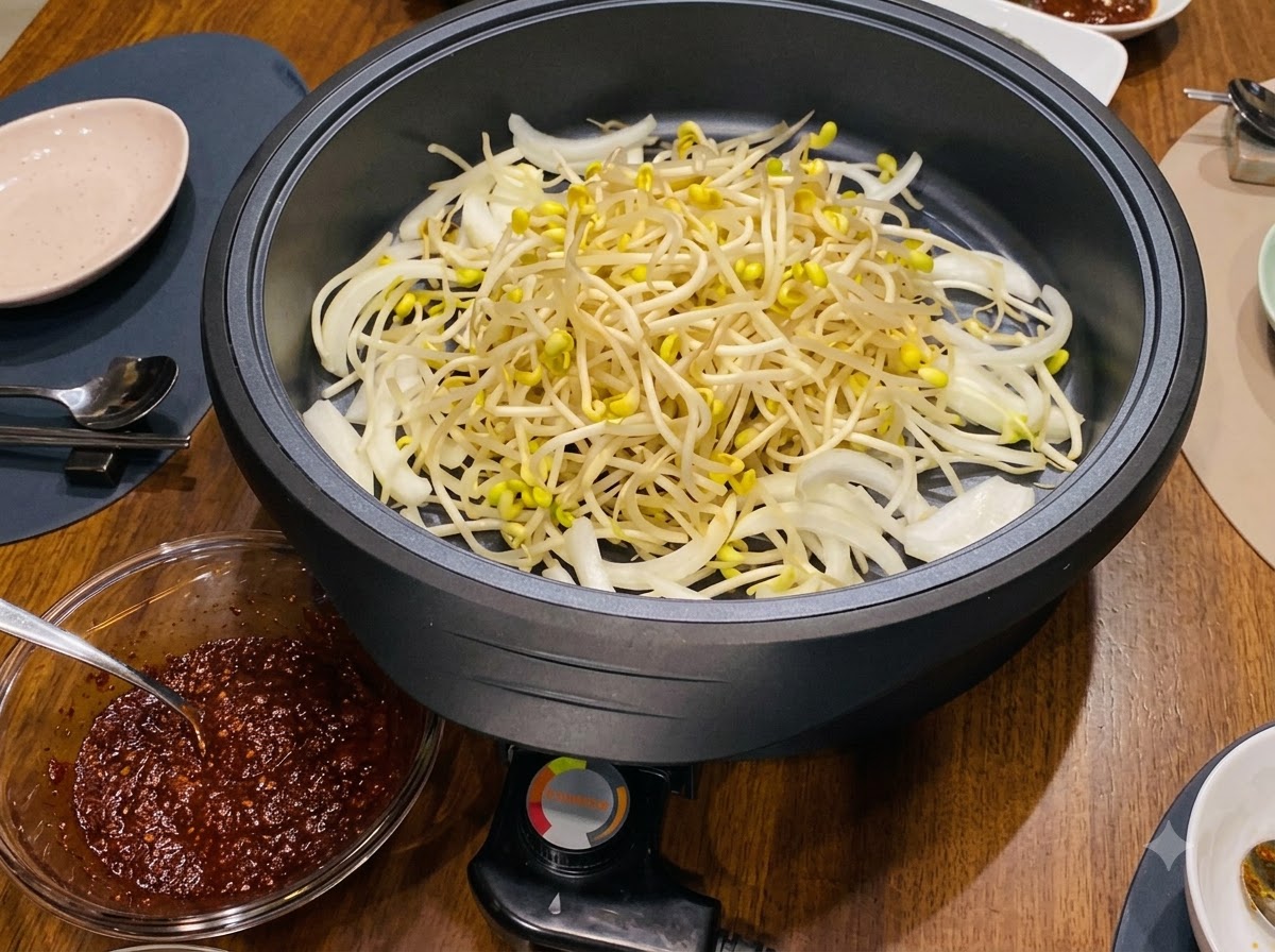 전기 팬 안의 양파 위에 노란 콩나물이 수북하게 쌓여 있습니다.