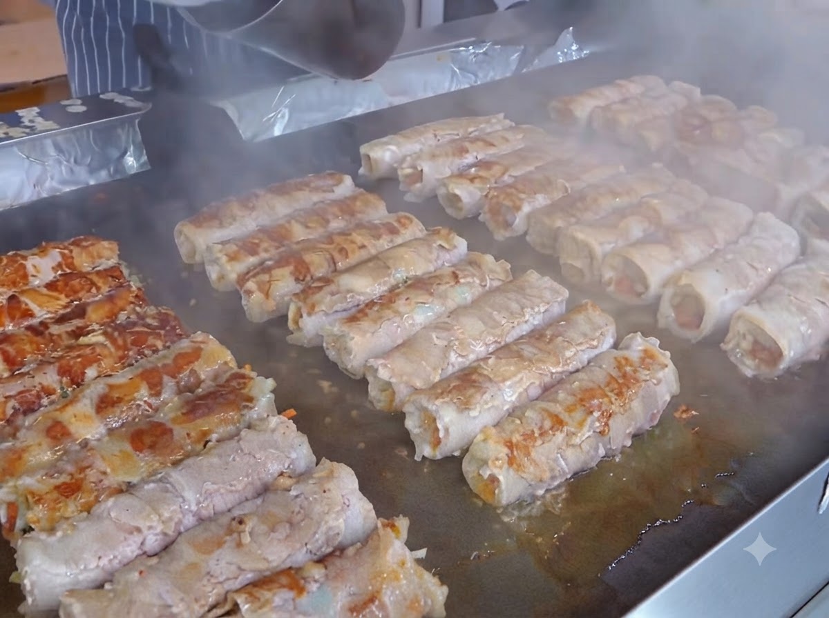준비된 고기말이 위 김치 층에 노란 슬라이스 치즈를 올리는 모습.