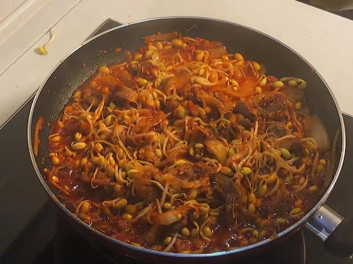 맛있게 조려진 콩불 위로 참기름을 살짝 두르는 모습.