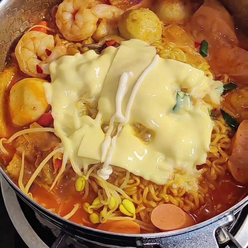 라면 위에 녹은 치즈 위로 마요네즈를 지그재그 모양으로 뿌리는 모습.